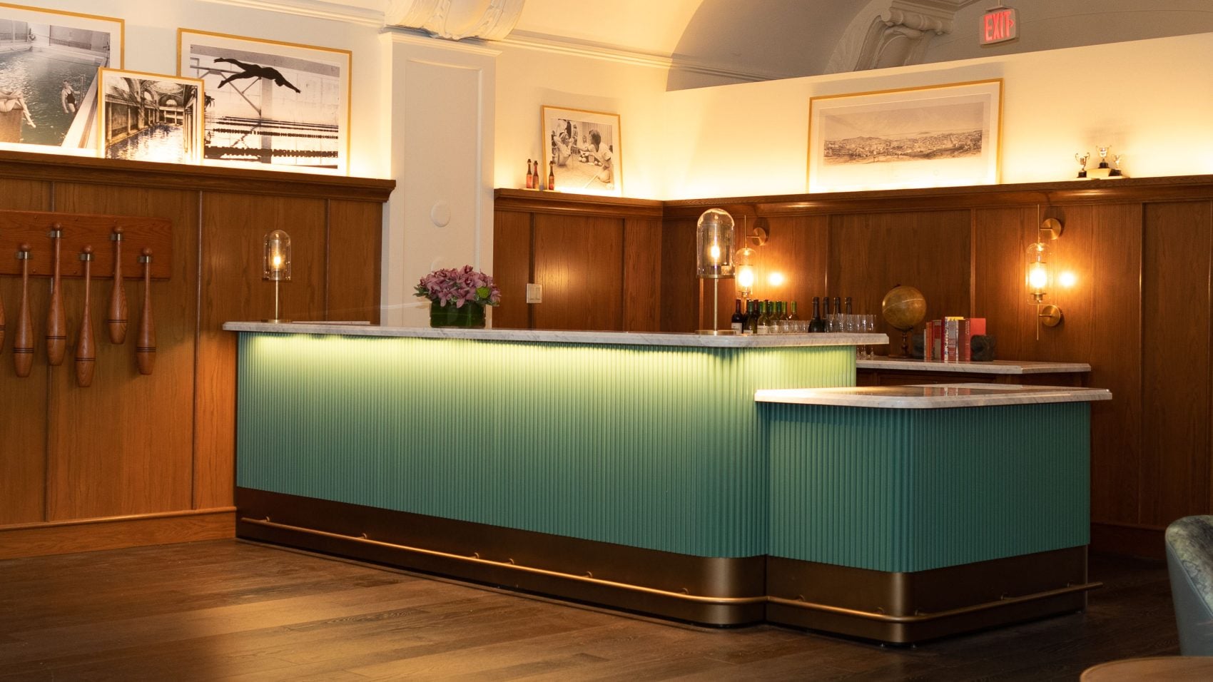 Modern hotel reception desk with green fluted panels, warm lighting, and wood paneling at Harbor Court Hotel