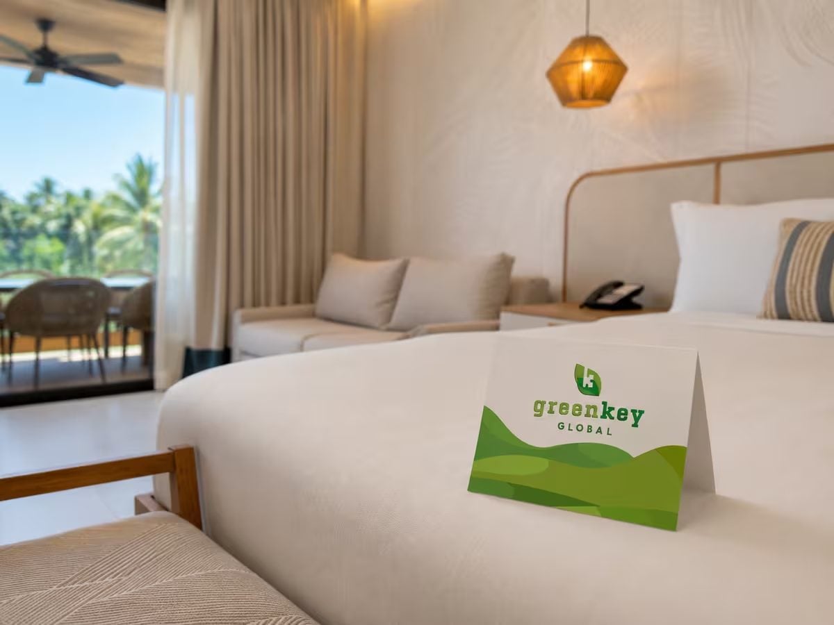 Hotel bed with a Green Key Global card on the linen