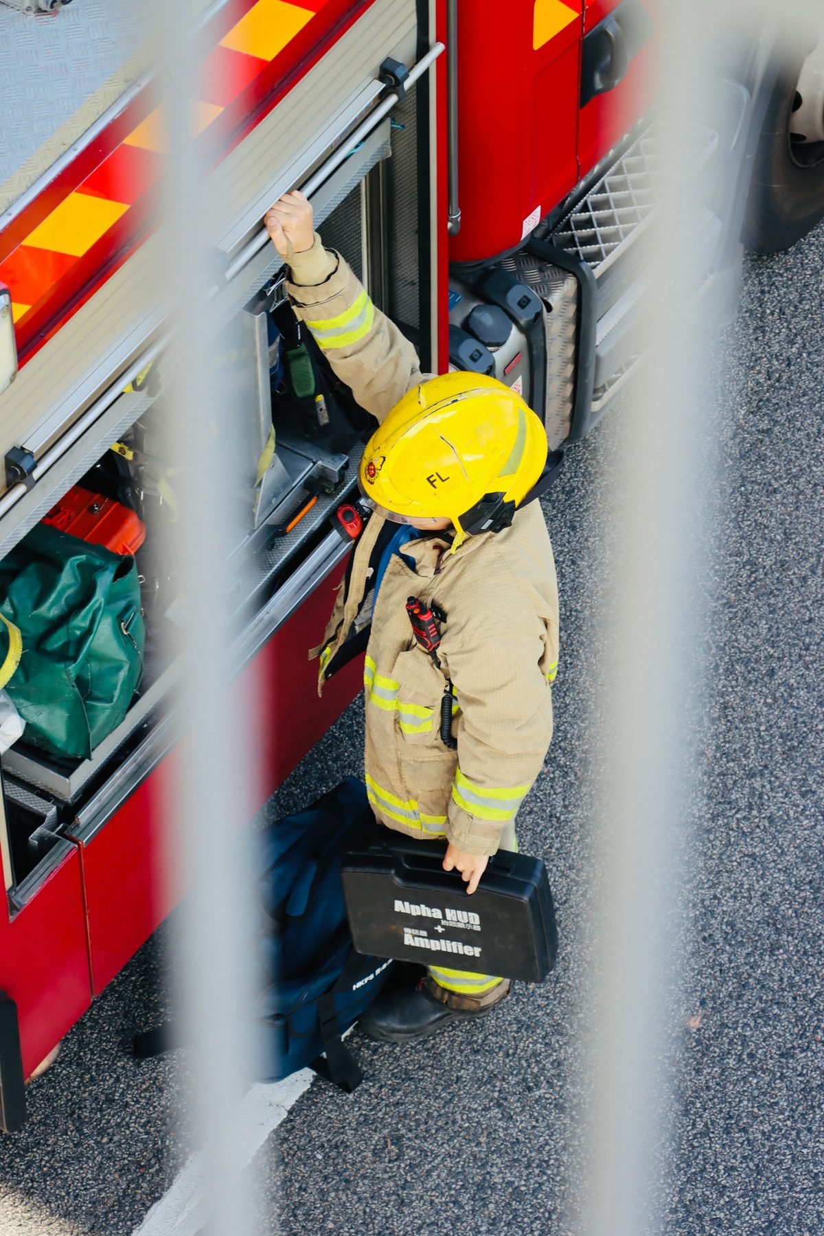 A firefighter in turnout gear beside a fire engine, seen from above