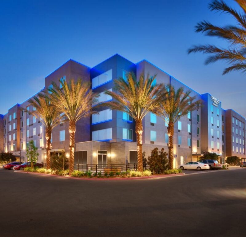 Modern hotel exterior with blue accent lighting and palm trees at dusk