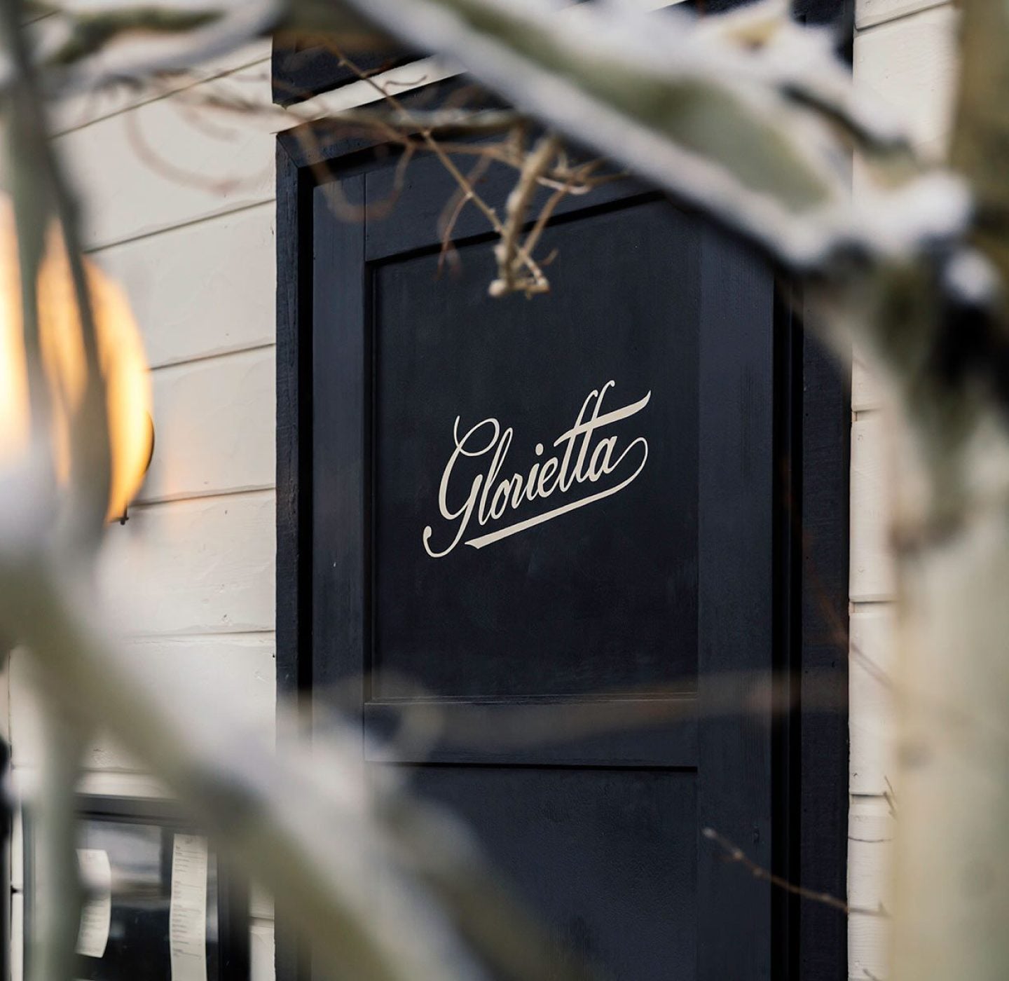 Dark blue hotel door with a Glorietta script sign seen through branches