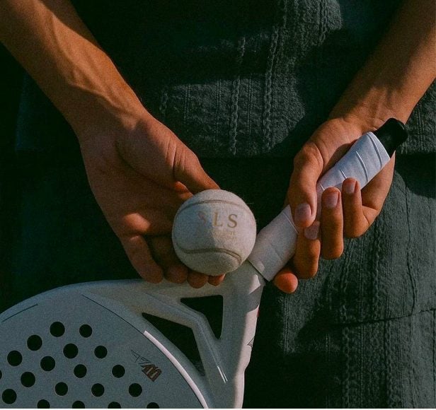 Hands holding a padel racket and ball