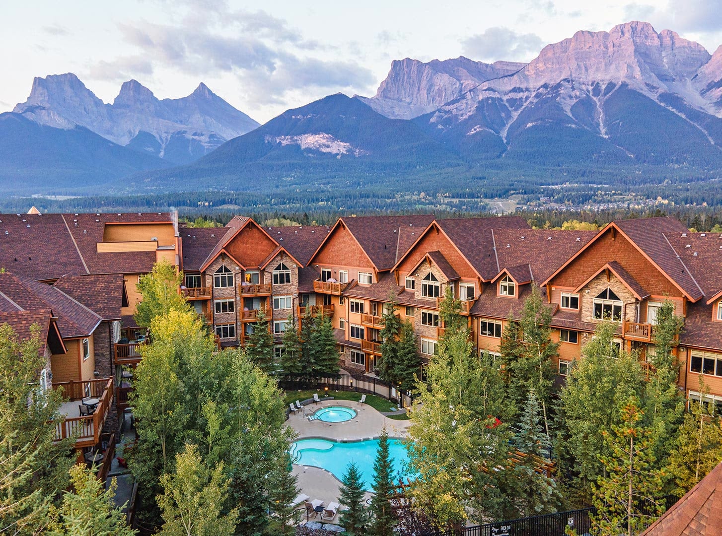 Timber lodge with a courtyard pool below rocky mountain peaks