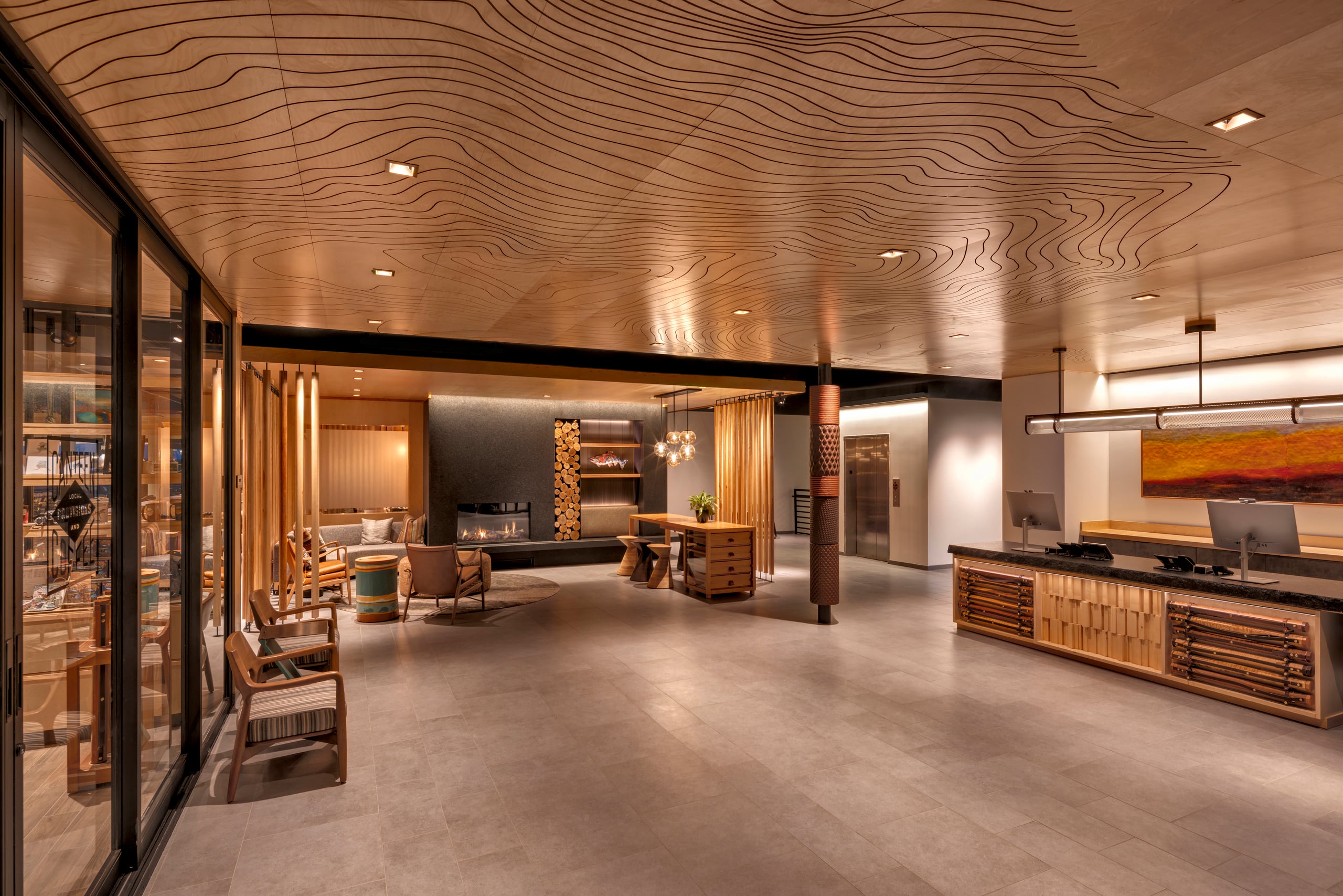 Spacious lobby at The Wildbirch Hotel featuring wooden check-in desks, lounge seating, and a fireplace.