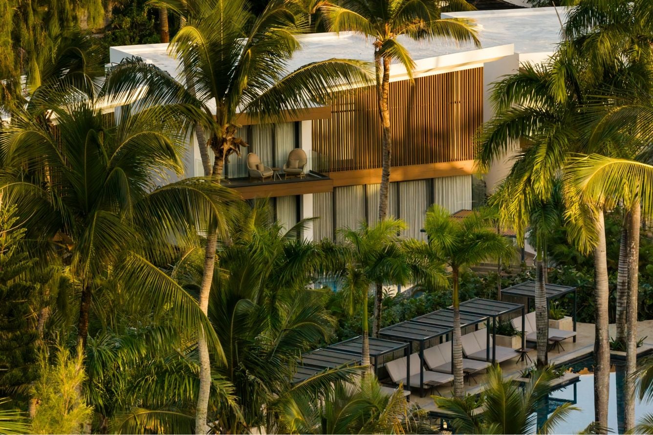 Resort villas surrounded by palm trees, with poolside cabanas at golden hour
